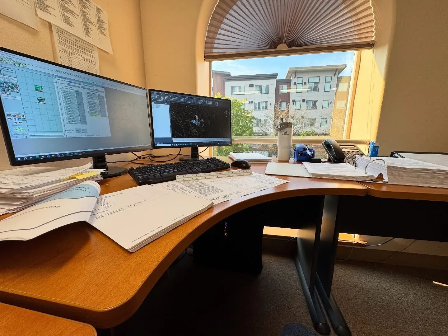 Drafting workstation running Civil 3D next to a survey point file and printed plan sets.